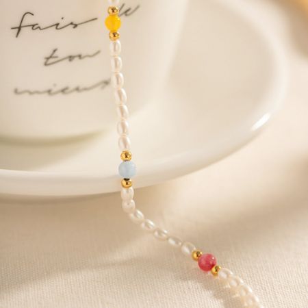 Gros plan du bracelet de cheville en acier inoxydable avec des perles et des perles multicolores.