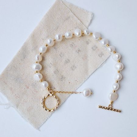 A beautifully crafted baroque freshwater pearl bracelet with gold accents and a toggle clasp, displayed on a neutral background.