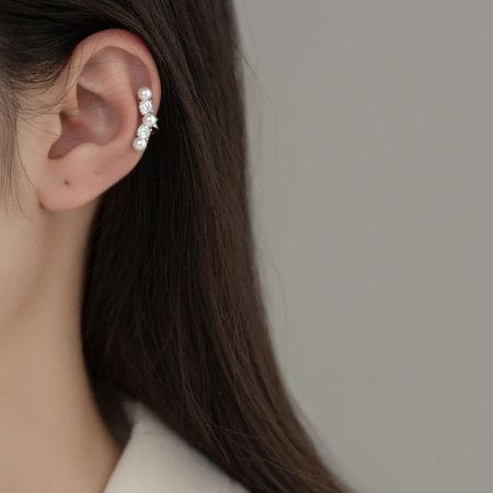 Primo piano di un orecchino a cuffia in argento sterling con perla indossato su un orecchio, evidenziando il suo design elegante e la vestibilità comoda.