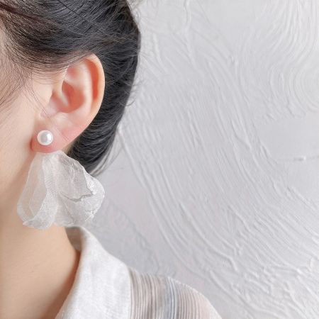 シングルパールイヤリングを着用したモデルで、その優雅なシンプルさを強調しています。