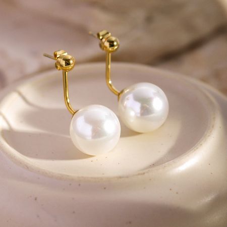 Close-up van het gouden haakontwerp op de Franse stijl parel oorbellen.