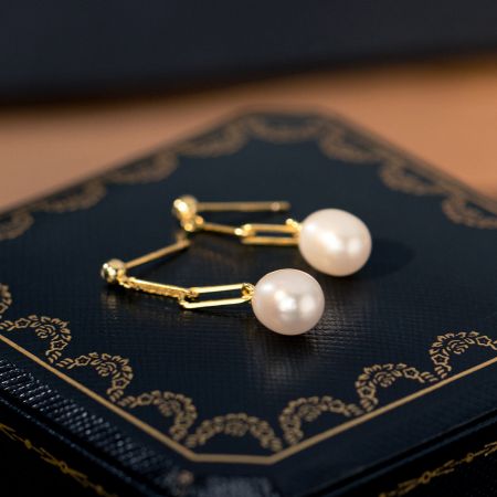 Una foto elegante degli orecchini a goccia in perla placcati in oro, che mostrano il loro design unico.