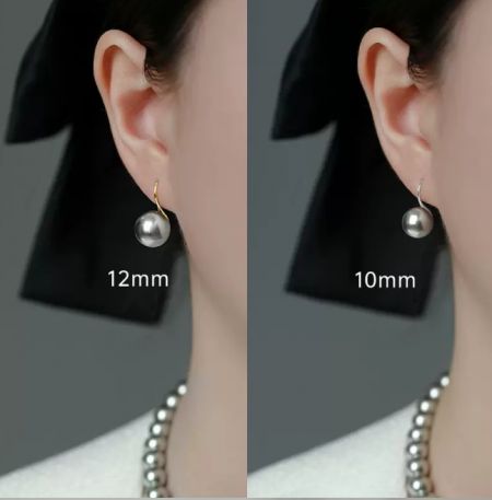 Confronto delle dimensioni degli orecchini a gancio in argento sterling 925 con perla grigia su un orecchio di un modello.