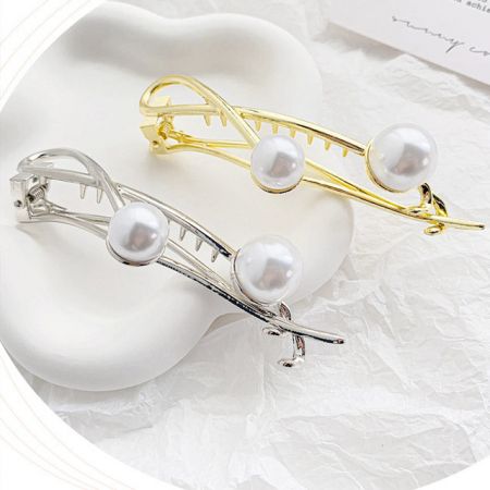 Two pearl-adorned hair clips in different metallic colors, showcasing the product variety.