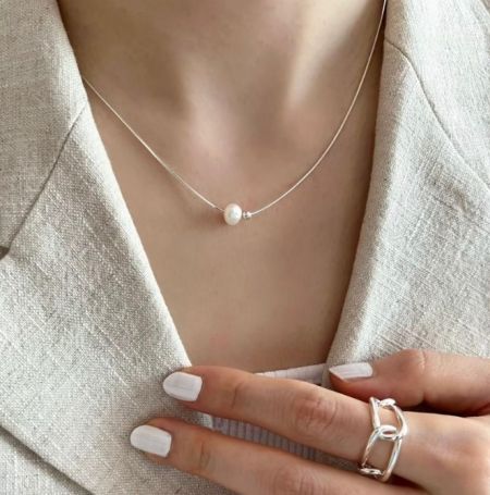 Collar tipo choker de plata esterlina 925 con una sola perla. - Una modelo luciendo elegantemente el collar tipo choker de plata esterlina 925 con una sola perla, mostrando su delicado diseño y la lustrosa perla de agua dulce.
