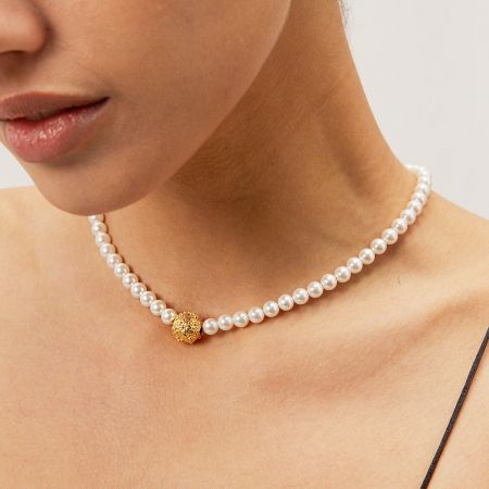 Charm de Bola Dorada de Acero Inoxidable con Collares de Cadena de Perlas (Conjunto de 5) - Una modelo lleva el elegante collar de cadena de perlas de acero inoxidable con un charm de bola dorada, mostrando su delicado diseño contra la piel.