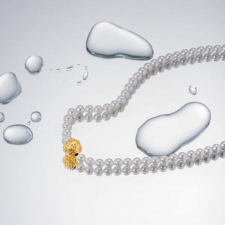 Eine andere Perspektive, die den eleganten Goldverschluss und die glänzenden Perlen der Kette hervorhebt.