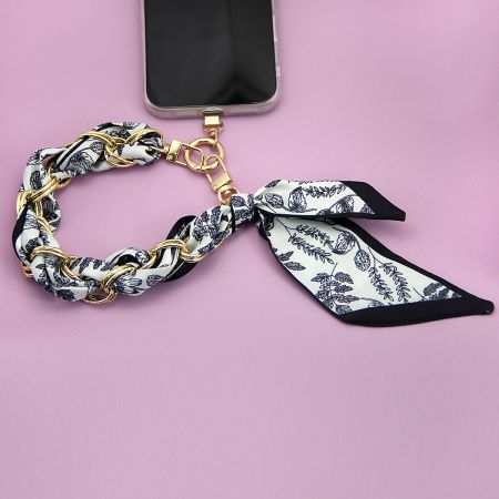 鮮やかな花柄ストラップと金のハードウェアを備えたスタイリッシュな携帯アクセサリー。