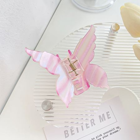 A close-up of a pink butterfly hair clip with a striped acetate pattern.