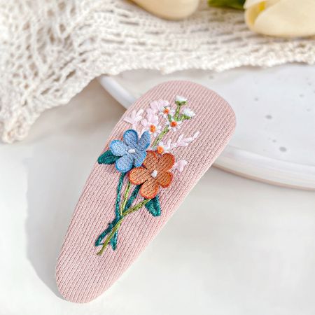刺繍された花柄のピンクのヘアスナップクリップ。