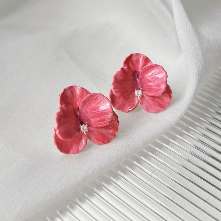 中央のジルコンを強調したピンクの花イヤリングの詳細ショット。