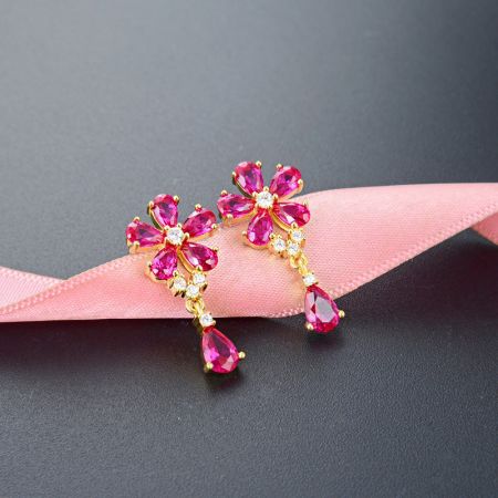 Primo piano degli orecchini a goccia con zirconia rosa a forma di fiore, mostrando l'intricato collegamento tra i due elementi floreali.