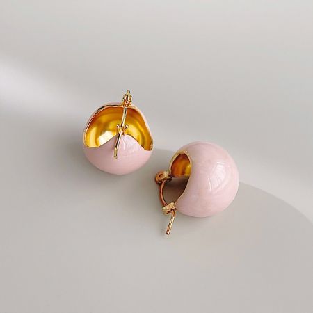 ピンクと金の球体イヤリングの詳細なビューで、空洞の金の内部を強調しています。
