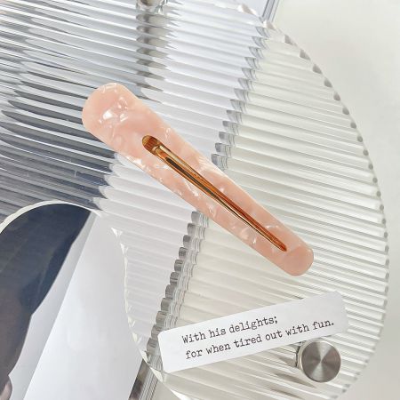 Een enkele roze acetaathaarclip met een glanzende gouden binnenkant.