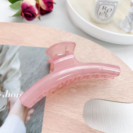 中立的な背景にエレガントなピンクのアーク形状のヘアクロークリップ。