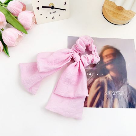 Vista dettagliata dell'elastico per capelli in morbido tessuto rosa.