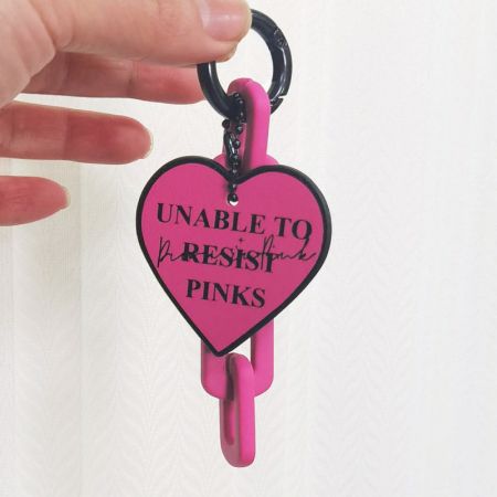 Le porte-clés en forme de cœur rose montré en utilisation avec une clé, soulignant son application pratique.