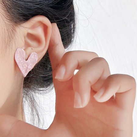 A model wearing the pink hammered heart stud earring to show its size and style.