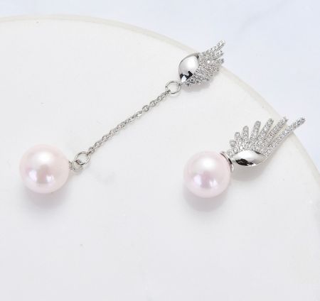 A pair of Angel's Wings earrings with pink pearls and silver chains, highlighting the crystal-studded wing design.