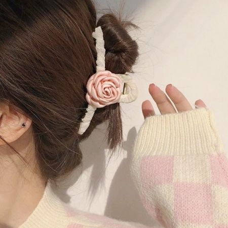 お団子ヘアスタイルの女性がピンクの椿の花のヘアクローを着用。