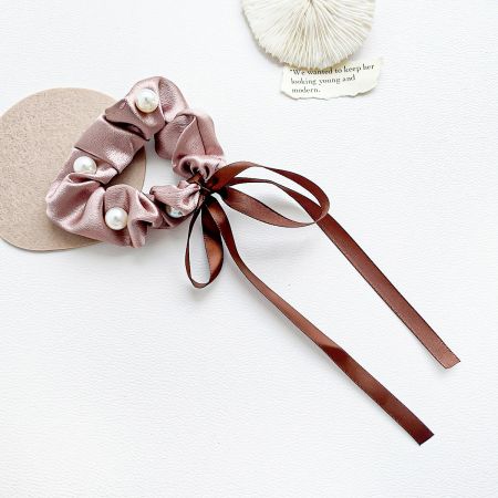 Detailed view of the pink satin scrunchie with beautiful pearl and ribbon accents.
