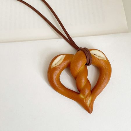 Gros plan sur le pendentif en forme de cœur en bretzel sur un cordon brun durable.