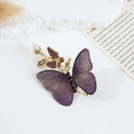 Close-up do broche de borboleta bordado roxo com detalhes em pérola falsa e ouro.