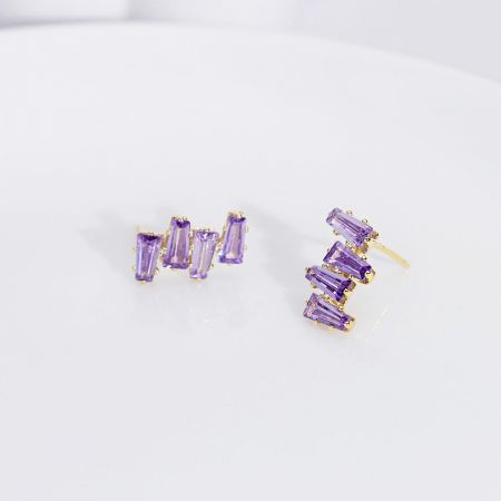 Un set di gioielli coordinato che include orecchini placcati in oro e un anello con cristalli baguette viola.