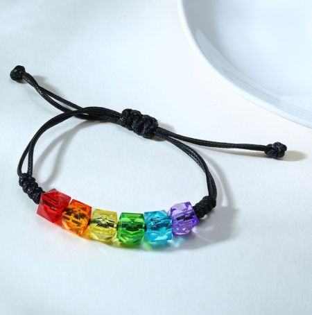 Primo piano delle vivaci perline acriliche color arcobaleno sul braccialetto pride da uomo.