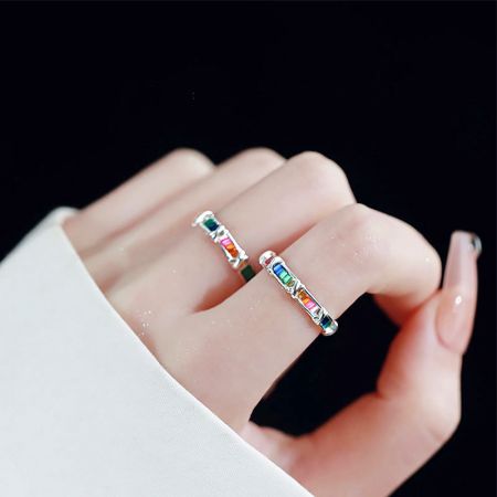 Dos anillos de zirconia arcoíris de plata esterlina llevados en la mano de un modelo para mostrar la escala.
