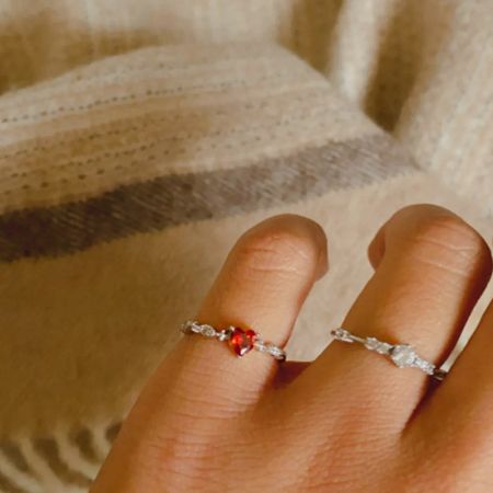 Une comparaison de deux styles de bagues, l'une avec une pierre précieuse rouge et l'autre avec des pierres blanches.