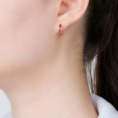 Modèle portant la boucle d'oreille créole Baguette Mini Huggies avec une pierre précieuse rouge vif, mettant en valeur son ajustement élégant.