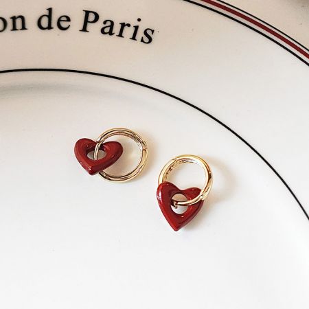 Stylish red heart and gold earrings displayed with a Paris-themed background.