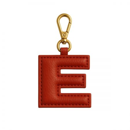 Portachiavi elegante in pelle rossa a forma della lettera 'E' con una clip dorata, un esempio di accessori personalizzati con iniziali.