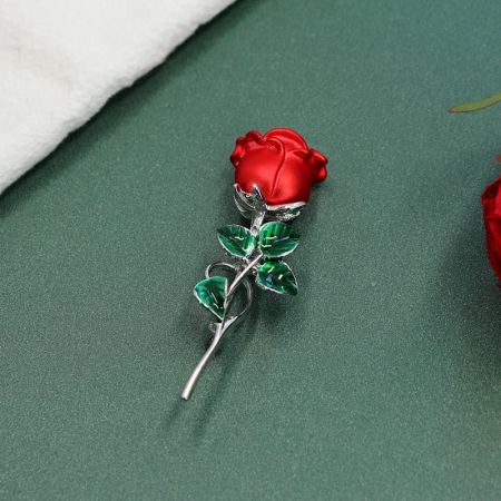 Een alternatieve hoek van de rode emaille rozenbroche met de veilige pin sluiting zichtbaar.