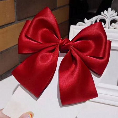 Scatto del prodotto della clip per capelli con fiocco in raso rosso vibrante.