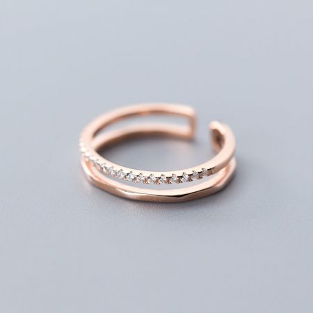 Close-up van een rosegouden ring met twee lagen en delicate edelsteenaccenten.