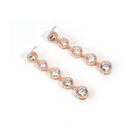 Vue latérale détaillée des boucles d'oreilles en cristal rose doré, mettant en valeur le sertissage complexe des pierres précieuses transparentes.