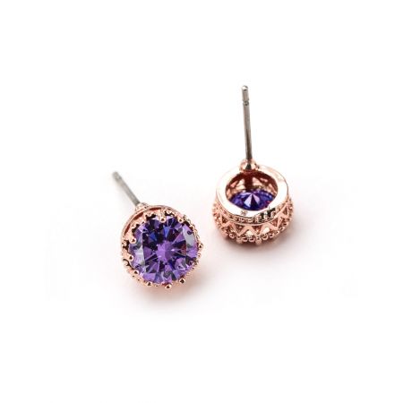 Une vue latérale détaillée des boucles d'oreilles en couronne à clou en or rose, mettant en valeur le sertissage complexe et la vibrante pierre précieuse violette.