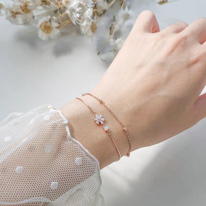 Model wearing the rose gold flower charm bracelet, showing its elegant fit on the wrist.