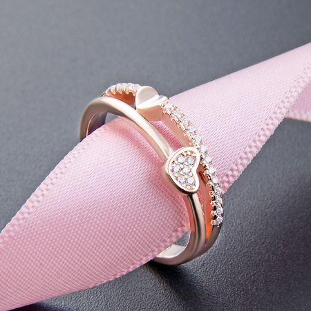 Set di 5 anelli a forma di cuore in argento sterling 925 placcati oro rosa a doppio strato con CZ - Un set di anelli in argento sterling 925 placcati in oro rosa con un design a cuore a doppio strato e pietre CZ scintillanti, esposti elegantemente su uno sfondo rosa chiaro.
