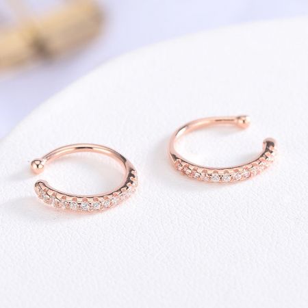 Eleganti orecchini a cuffia in oro rosa con brillanti pietre simili a diamanti.