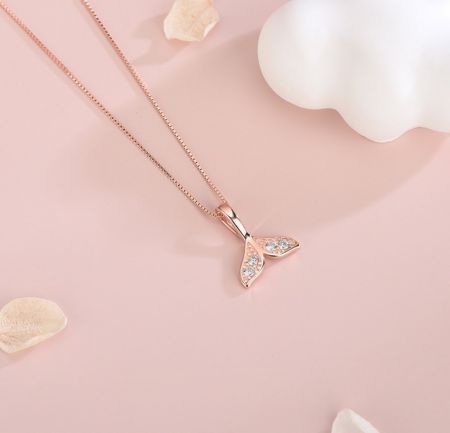 Primer plano del colgante de collar con cola de sirena en oro rosa, destacando las piedras de circonio cúbico brillantes.