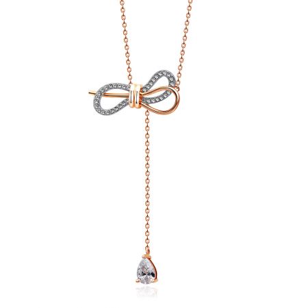Detalhe em close do intrincado pingente de laço cravejado de diamantes na corrente de ouro rosa.
