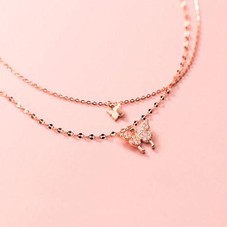 Close-up of two rose gold butterfly necklaces with delicate charms.