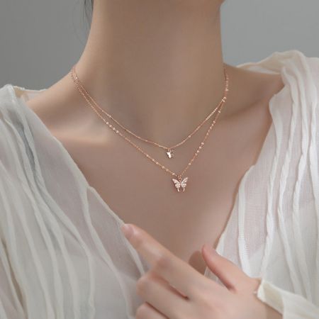 Model wearing the layered rose gold butterfly and star pendant necklaces.