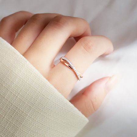 Eine Frauenhand, die den eleganten Möbius-Ring aus Roségold präsentiert und seine Passform und Brillanz zeigt.