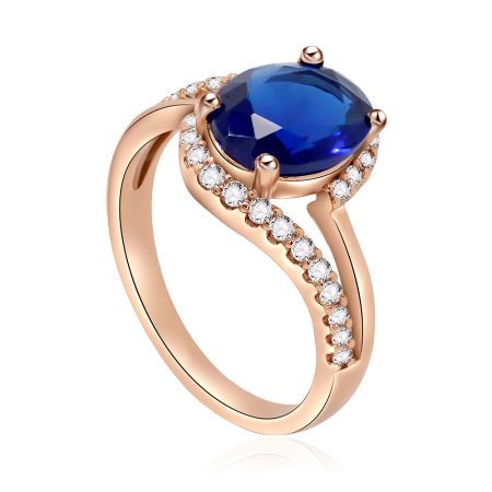 Vinklad vy av ringen i roséguld med safir och diamanter, som betonar dess lyxiga glans och intrikata svängdesign.