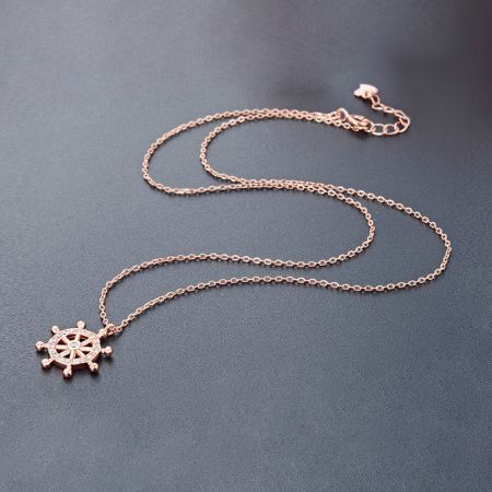 Elegant rose gold ship's wheel pendant necklace, showcasing its warm tone and brilliant stone embellishments.