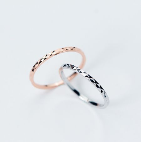 Bague en argent sterling 925 avec taille de diamant. - Une paire de bagues en argent sterling 925 avec taille de diamant, l'une en argent et l'autre avec un plaquage en or rose, mettant en valeur la finition texturée.